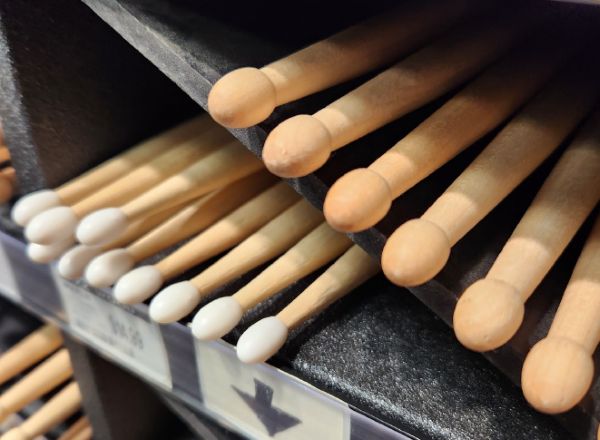 A bin of wooden and nylon tipped drumsticks for sale