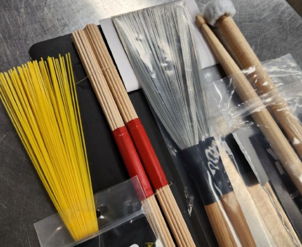 Drumstick alternatives such as brushes, mallets, and multirods laying on a table