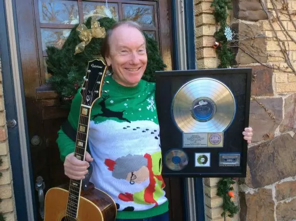 Randy Brooks, creator of Grandma Got Run Over By A Reindeer, posing with his golden framed record