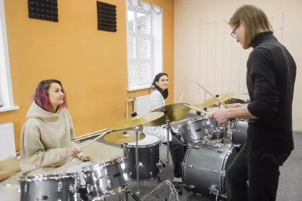2 Women taking an in-person drum class with a teacher