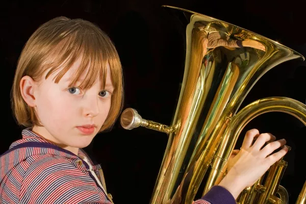 A man playing the Euphonium outside with an ocean in the background