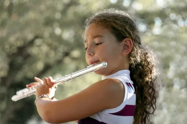 female child playing the Flute outside