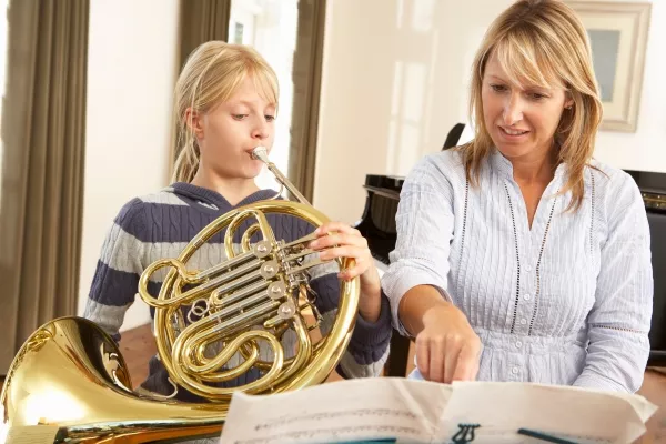 A female child taking private french horn lessons with a female teacher