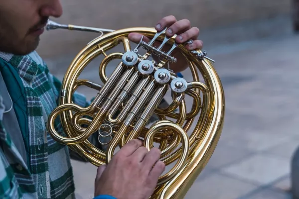 A side view image of a man holding a french horn