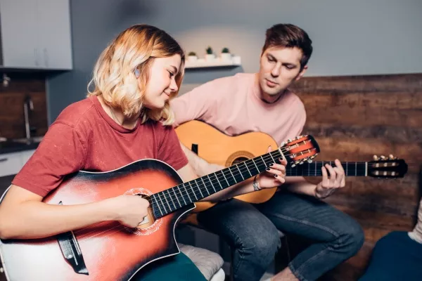 A man and woman playing the guitar together