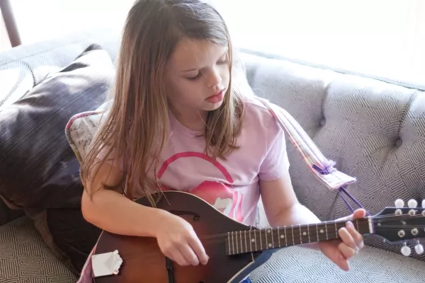 A female child playing the Mandolin on the couch