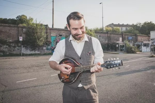 A male playing the Mandolin outside