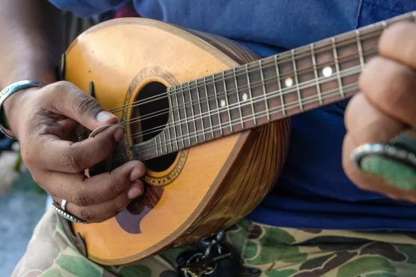 A zoomed in picture of a male playing the Mandolin at home