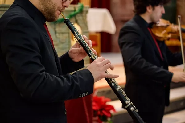 An adult male playing the oboe during an orchestrated performance