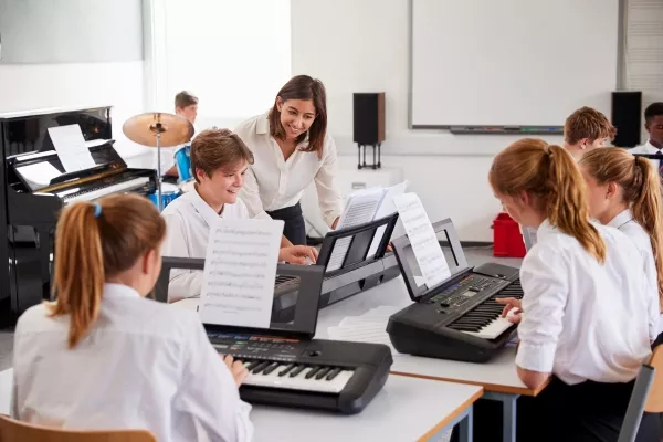 A teacher teaching a class of students chords on a piano
