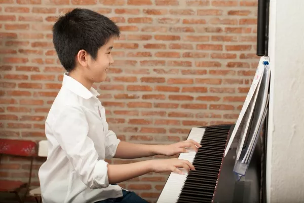 male child playing the Piano and smiling
