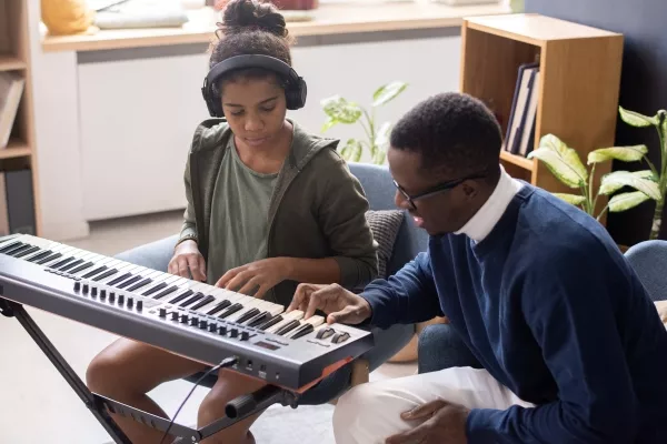 A teen taking a private piano class with a teacher