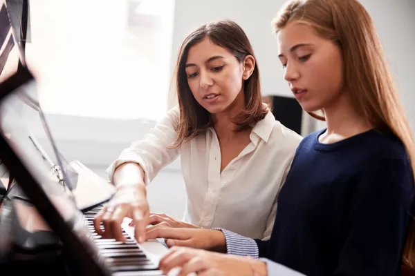 Female teen taking piano lessons with a teacher