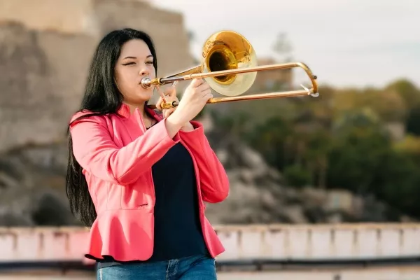 A woman playing trombone outside