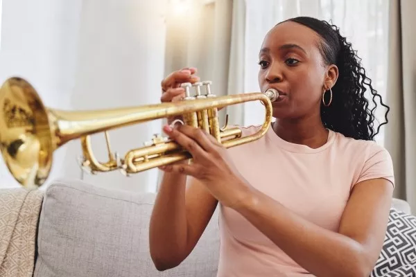 A female teen playing the trumpet at home on the couch