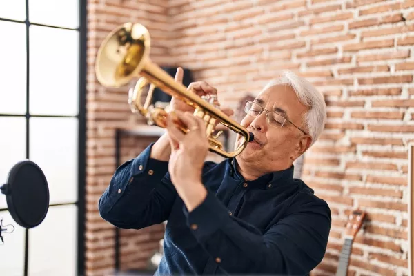 A senior enjoying the trumpet at home in front of a microphone