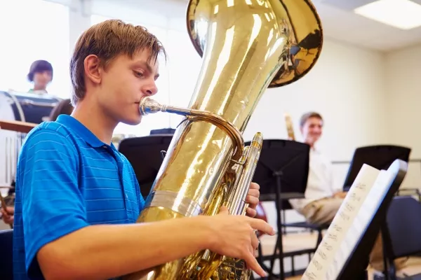 A student playing the tuba in his music class