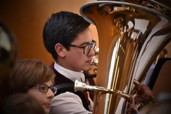 A male dressed nicely playing the tuba in an Orchestra