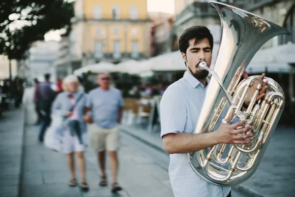 A man playing the tuba outside in the city street