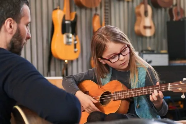 A child taking private Ukulele lessons with a teacher