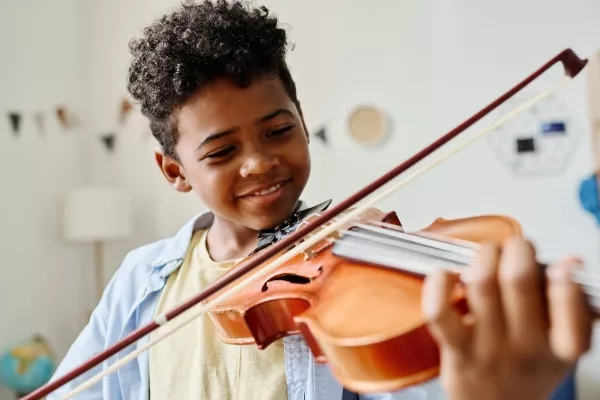 A child smiling and playing the violin