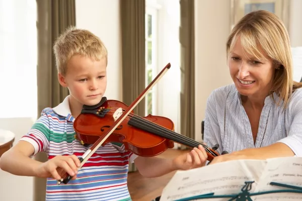 A child playing the Violin during private violin lessons with his teacher