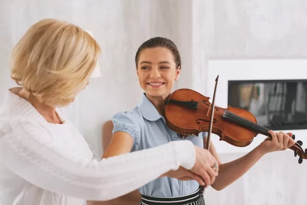 A female taking private Violin lessons with a teacher