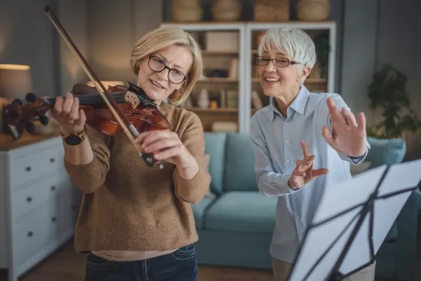 A woman taking at home violin lessons with a teacher