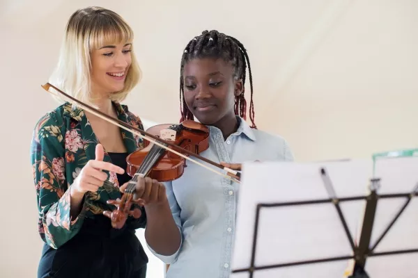 Female teen attending Violin lessons with her teacher next to her